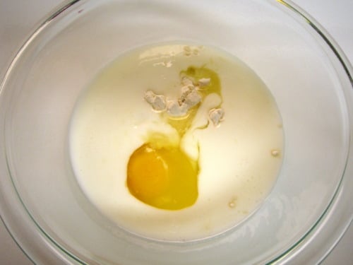 Egg, buttermilk, and dry ingredients combined in a mixing bowl before whisking.