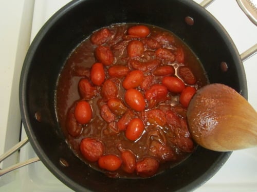 Cherry tomatoes simmering in a pot of curried ketchup sauce.