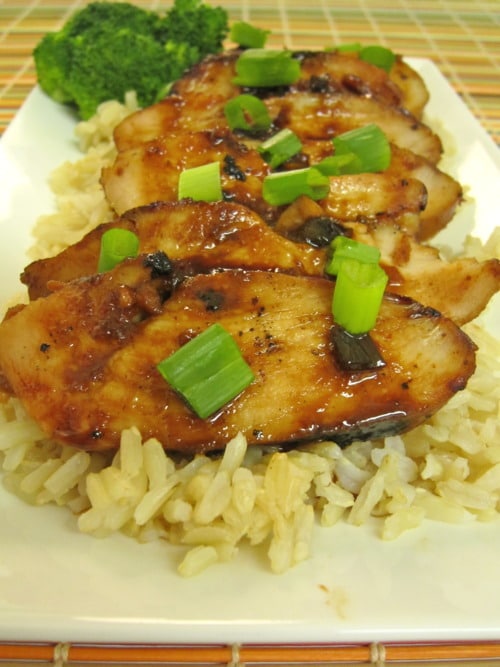 Asian-style chicken breasts on rice with green onion garnish