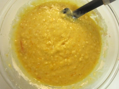 Orange marmalade muffin batter in a mixing bowl with a black spatula.