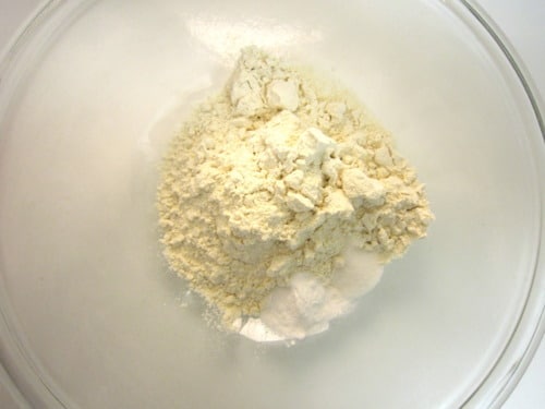Flour, baking soda, and salt combined in a glass mixing bowl, prepared as dry ingredients for banana oatmeal chocolate chip cookies.