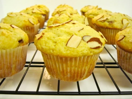 Almond-topped jam-filled muffins cooling on a wire rack.