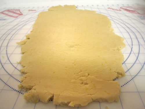 Rolled out lemon cookie dough on a pastry mat, prepared for mini strawberry-filled lemon sandwich cookies.