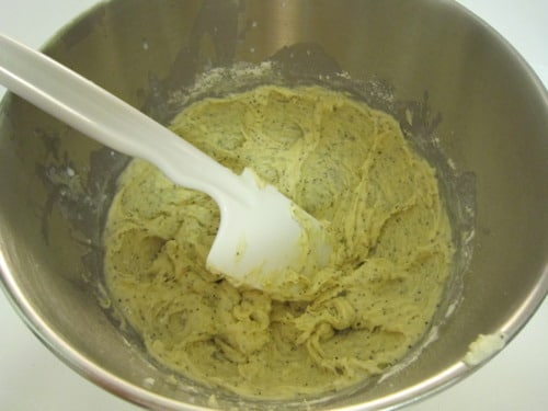 Lemon poppy seed donut batter mixed in a metal bowl with a spatula.