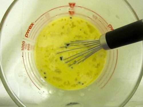 Whisk mixing egg and milk custard in a Pyrex measuring bowl for cinnamon baked French toast.
