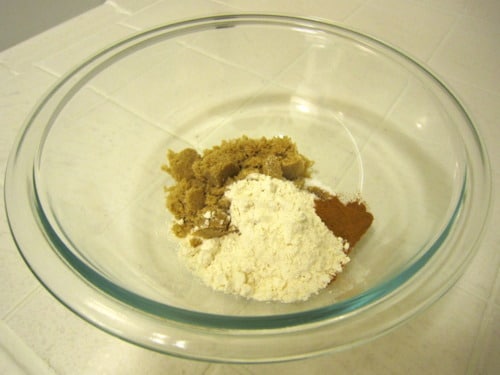 A glass mixing bowl containing brown sugar, flour, and cinnamon for making cinnamon baked French toast.