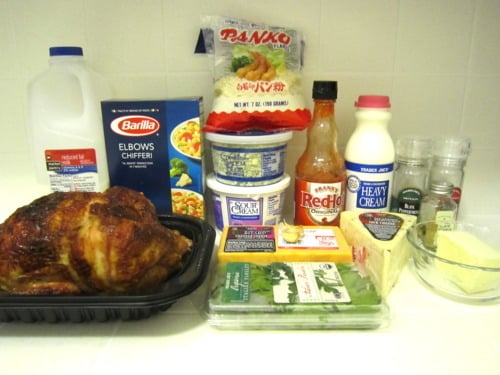 Ingredients for buffalo chicken macaroni and cheese including rotisserie chicken, elbow pasta, milk, heavy cream, cheddar cheese, cream cheese, sour cream, hot sauce, butter, panko breadcrumbs, spinach, and seasonings.