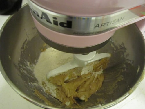 Stand mixer with paddle attachment blending cookie dough with flour and creamed ingredients for soft and chewy chocolate chip cookies.