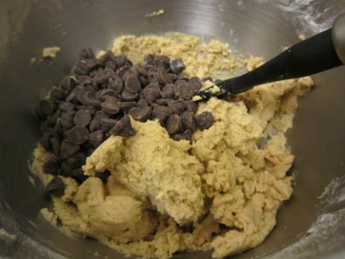 Chocolate chip cookie dough in a mixing bowl with a spatula, ready to be mixed for soft and chewy chocolate chip cookies.