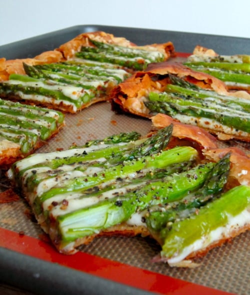 Asparagus and Gruyère tart cut into rectangular slices on a baking sheet.