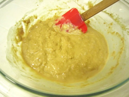 Cappuccino pancake batter mixed in a glass bowl with a red spatula, showing a smooth, thick consistency.