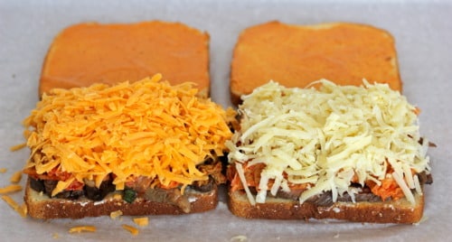Open-faced kalbi steak and kimchi grilled cheese sandwiches topped with shredded cheddar and mozzarella on toasted bread, ready to be assembled.