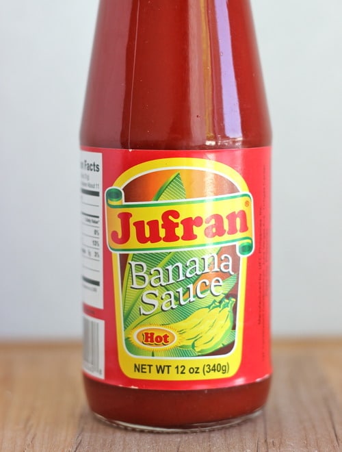 A bottle of Jufran Hot Banana Sauce standing on a wooden surface.