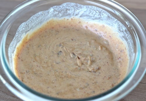 Creamy lime sauce for fish tacos in a glass bowl, lightly speckled with seasoning and freshly mixed.