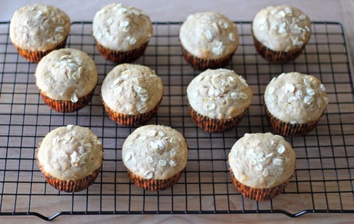Orange cinnamon honey muffins topped with oats cooling on a wire rack.