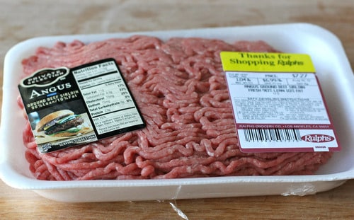 Packaged raw ground Angus beef in a white foam tray with nutrition and store labels.