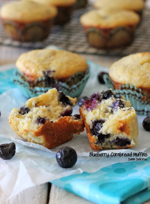 Blueberry cornbread muffins with one muffin broken open to show blueberries inside.