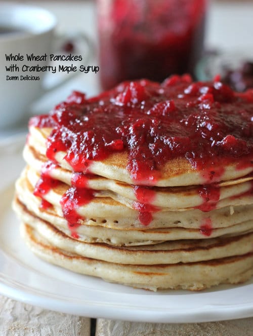 A tall stack of whole wheat pancakes topped with a generous layer of cranberry-maple syrup.