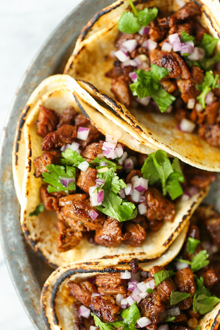 Street tacos served with onion, cilantro, and lime on corn tortillas