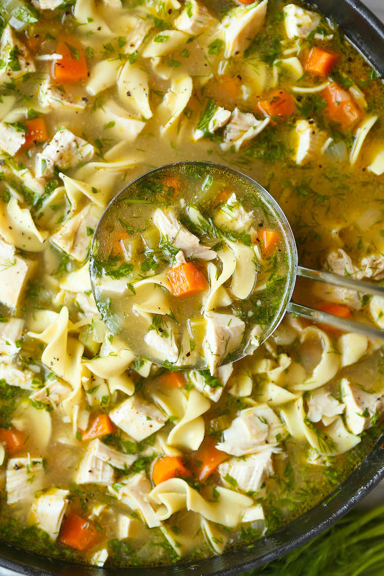 Ladle serving chicken noodle soup with egg noodles, chicken, and vegetables