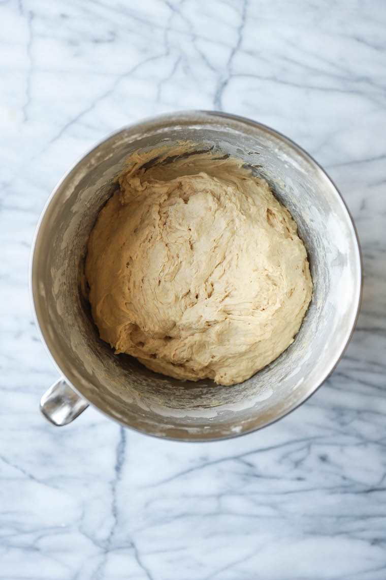Kneading homemade pizza dough on a floured countertop, with visible texture and movement in the dough.