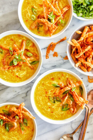 Bowls of Egg Drop Soup, served with won ton strips, and garnished with green onions.