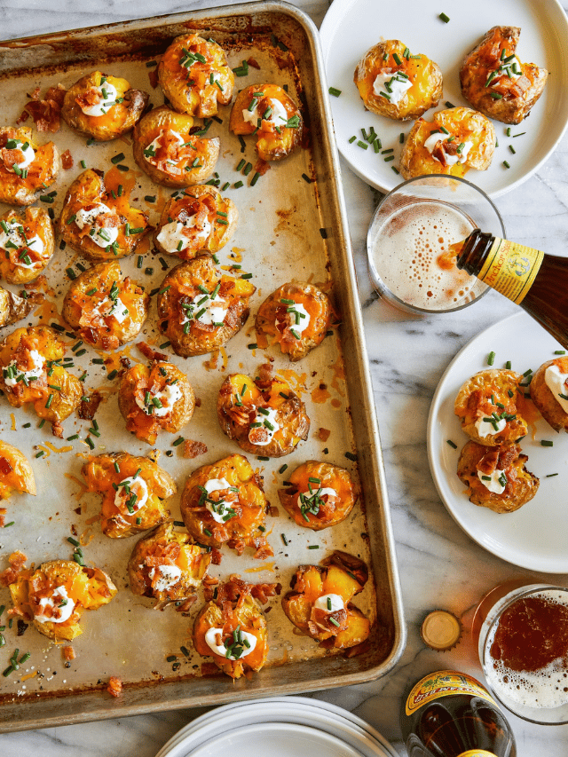 Super crispy smashed potatoes topped with sour cream, bacon and chives, resting in an oven pan.