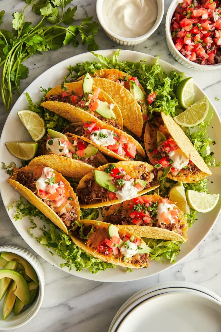 Baked Tacos - Crispy oven baked tacos! Made with hard taco shells, ground beef, taco seasoning, cheese, pico de gallo, sour cream + avocado!